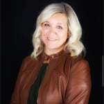 A person with blonde hair wearing a brown leather jacket

Description automatically generated