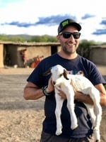 A person holding a goat

Description automatically generated